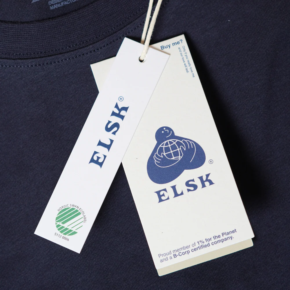 An ELSK garment with its Buy Me hang tag showing the B Corp and 1% for the Planet marks